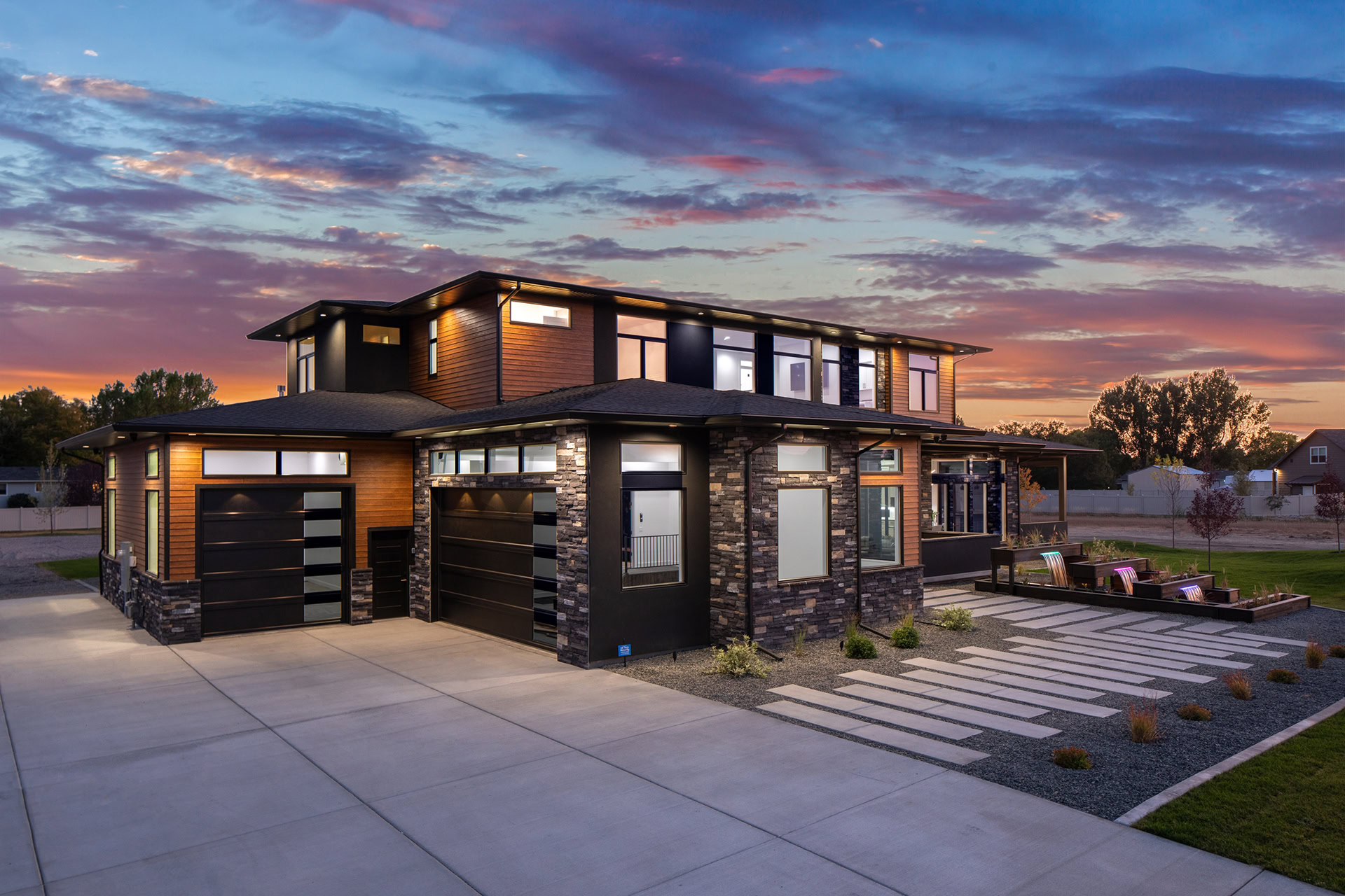 Modern two-story house with sleek design and large windows at sunset.